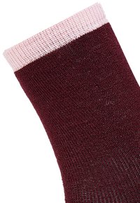 Tummanpunainen sukka, jossa on teksturoitu pinta ja vaaleanpunainen resorireuna. Materiaali näyttää neulotulta, sileältä ja joustavalta.