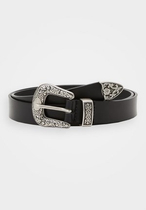 Ceinture en cuir noire avec boucle florale gravée couleur argent, passant et embout, roulée à plat sur un fond blanc.