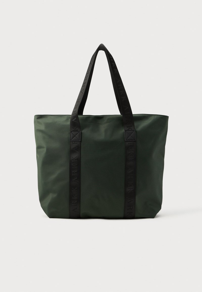 Bolsa de tela de nailon verde con asas negras de marca, forma rectangular, textura suave y diseño minimalista.