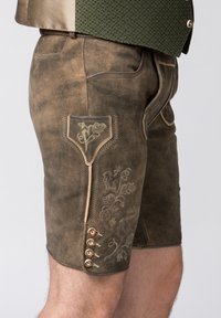 Shorts en cuir marron avec broderies décoratives et détails de couture traditionnelle. Comprend une poche avec broderie et des boutons décoratifs.