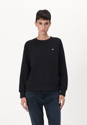 Felpa nera realizzata in misto cotone, con maniche lunghe, colletto a girocollo, polsini a coste e un piccolo logo sul petto. Tessuto liscio.