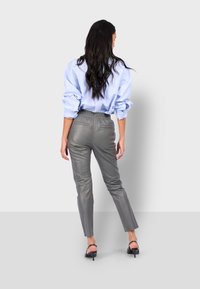 Šedé kožené kalhoty s elastickým pasem, úzkým střihem a dvěma zadními kapsami, v kombinaci s oversized světlemodrým tričkem.