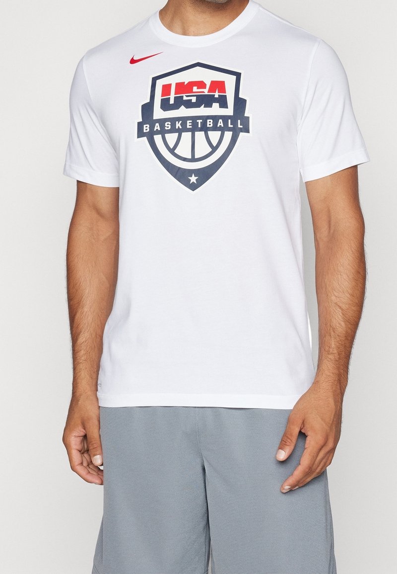 Bílý bavlněný tričko s kulatým výstřihem, uprostřed s velkým logem USA Basketball v modré, červené a černé barvě. Krátké rukávy.