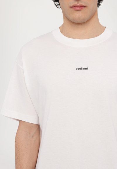 Tricou alb din bumbac, cu mâneci scurte și guler rotund, având un mic logo imprimat de culoare neagră "soulland" pe piept.