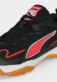Μαύρο αθλητικό παπούτσι Puma με κόκκινο και λευκό λογότυπο, μαύρα κορδόνια, υφασμάτινο επάνω μέρος και λεπτομέρεια στη σόλα σε χρώμα καουτσούκ.