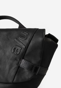 Schwarze Tasche aus strukturiertem Synthetikmaterial. Verfügt über einen Klappenverschluss, geprägtes Branding und einen glatten Lederakzentriemen.