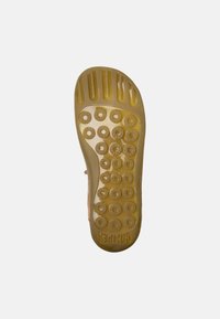Shoe sole made of yellow rubber with circular traction patterns, raised ridges, and the brand "Camper" printed near the heel.