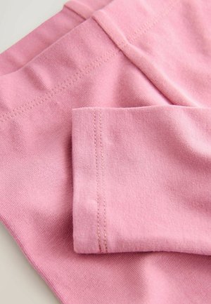 Helles rosa Gewebe mit glatter Textur, das gestickte Nähte aufweist. Das Bild konzentriert sich auf die Falten des Materials und die Details der Manschette.
