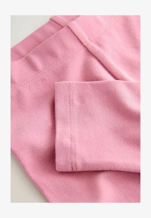 Világos rózsaszín anyag, sima textúrával, varrott varratokkal. A kép az anyag hajtására és a mandzsetta részletére összpontosít.