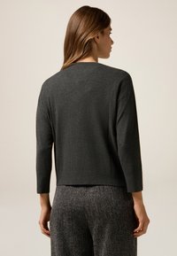 Mörkgrå, lättviktströja med en kortad design, trekvartsärmar och rundad halsringning, i kombination med strukturerade grå byxor.