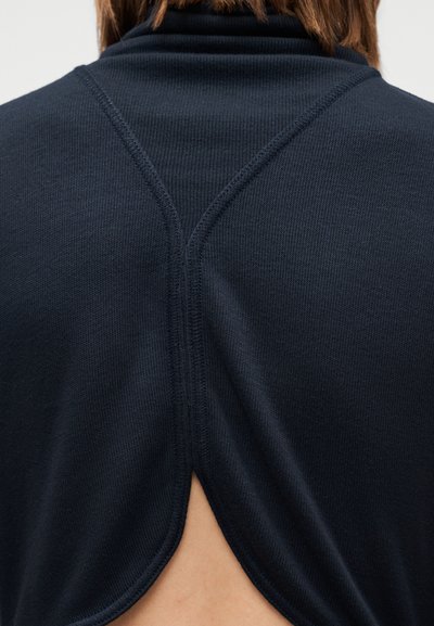 Tengerészkék felső magas gallérral és hátul kivágással. Texturált kötött anyagból készült, és a gerinc mentén látható varrásdíszítéssel rendelkezik.