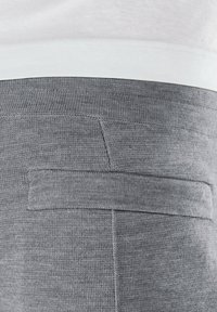 Grijze gebreide broek met een gladde textuur en een achterzak. De tailleband heeft een lichtblauwe accentuering en een gelaagd ontwerp.