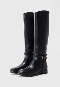 Knee-high black leather boots with a smooth texture, accentuated by two horizontal straps featuring a gold buckle detail. Flat sole.