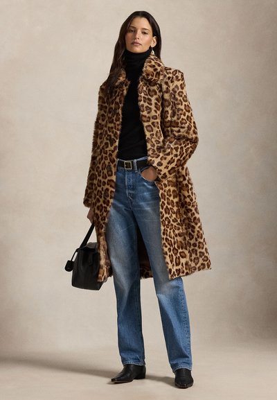Kabát z umelej kožušiny s leopardím vzorom, čierny rolák, modré džínsy, čierny opasok a členkové čižmy, doplnené malou čiernou kabelkou.