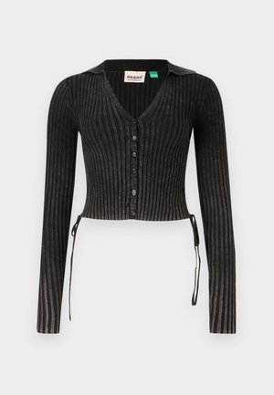 Svart ribbet cropped cardigan med lange ermer, V-hals, knappelukking og sidesnører. Har et strukturert strikkemønster.