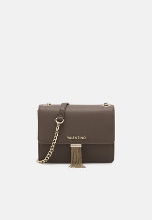 Sac bandoulière marron Valentino avec sangle chaîne dorée, détail pompon et logo sur le rabat avant, sur fond clair uni.