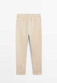 Beige joggingbroek met een elastische tailleband en verzamelde boorden. Zacht stof, gladde textuur en minimalistisch ontwerp.