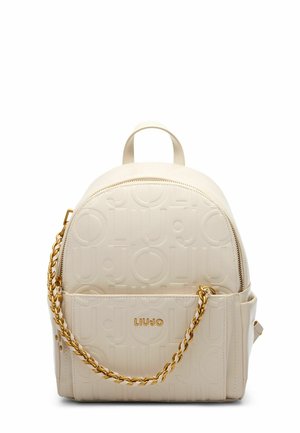 Zaino in ecopelle beige con motivo logo in rilievo, forma arrotondata, hardware in catena dorata e chiusura con zip. Presenta una maniglia superiore e una tasca laterale.