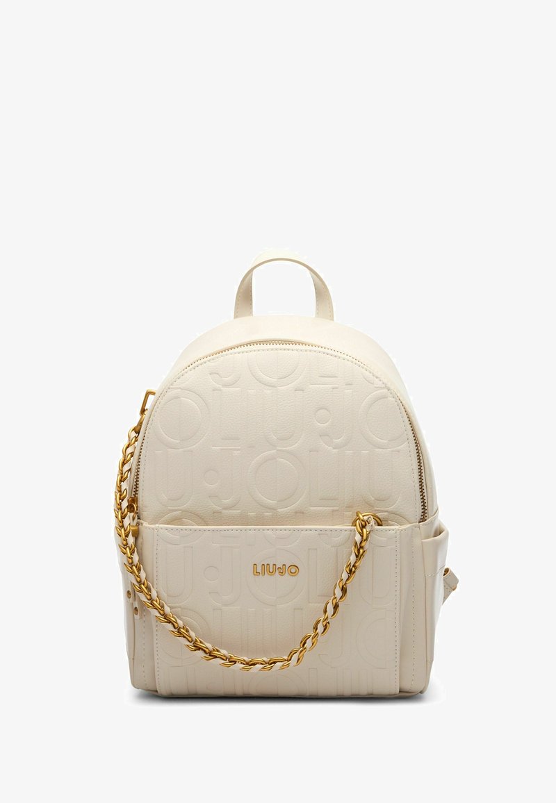 Zaino in ecopelle beige con motivo logo in rilievo, forma arrotondata, hardware in catena dorata e chiusura con zip. Presenta una maniglia superiore e una tasca laterale.