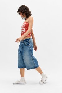 Culottes de mezclilla azul claro con un corte holgado, que cuentan con un diseño clásico de cinco bolsillos y detalles de costura sutiles. Combinados con un top corto gráfico rojo.