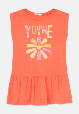 Top sem mangas cor-de-rosa coral com barra franzida. A parte da frente apresenta a frase "TU ÉS UM/A" em letras brilhantes acima de um design de flor com detalhes em glitter.