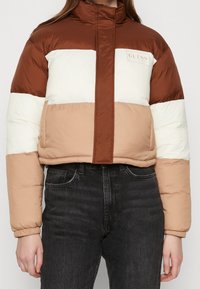 Brązowa, beżowa i biała kurtka puchowa z kolorowymi blokami, z wysokim kołnierzem i zamkiem z przodu, z naszywką logo na lewej piersi.