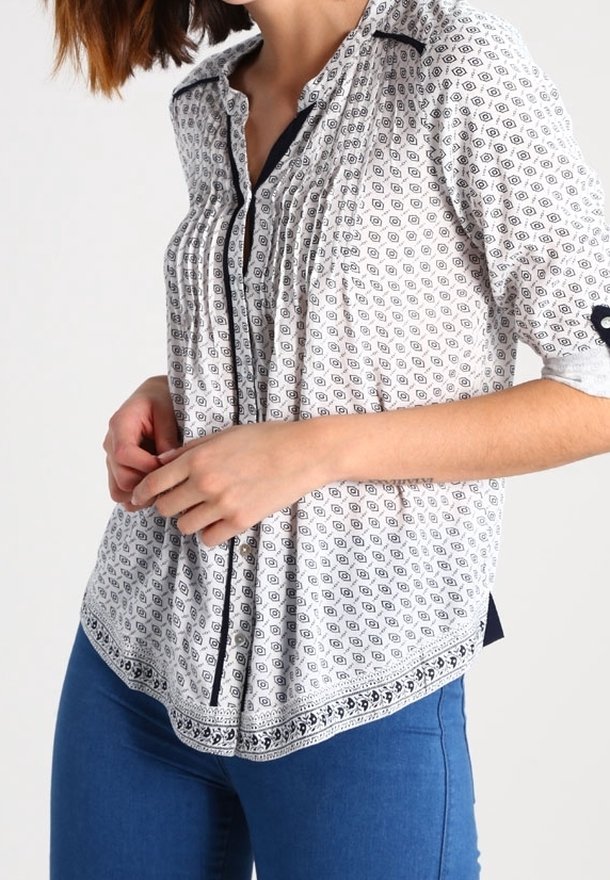 Blusa a maniche triple con motivo bianco e nero, dotata di un'apertura con bottoni, pieghe e orlo arrotondato; realizzata in tessuto leggero.