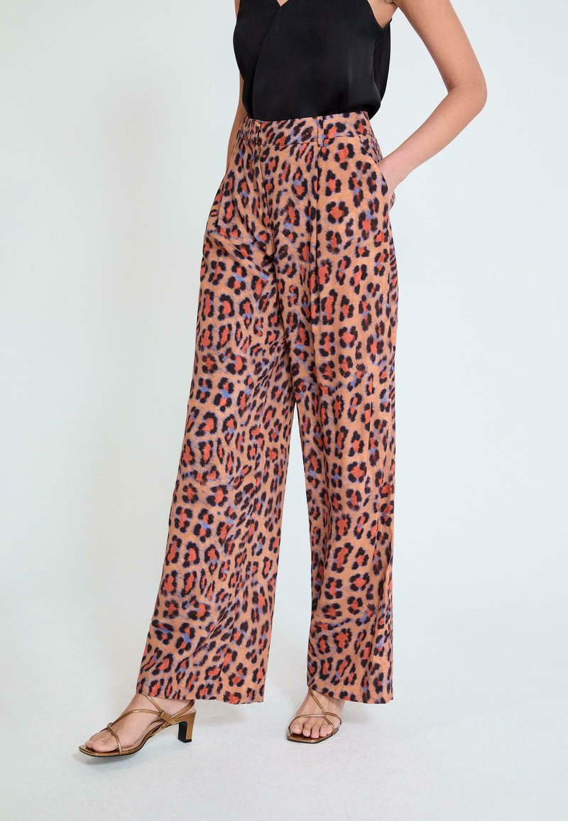 Pantalones de pierna ancha con estampado de leopardo en tonos marrones, naranjas y negros, con cintura alta y bolsillos laterales. Tejido suave y liso.