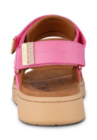 Pink sandal with adjustable straps, a cushioned brown footbed, and a light beige rubber sole. Features a woven accent on the strap.