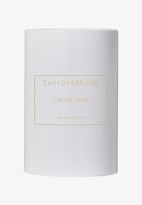 Biała cylindryczna butelka perfum z złotymi akcentami, z minimalistycznym projektem, na którym znajdują się etykiety "ZARKOPERFUME" i "CARATE URIO".