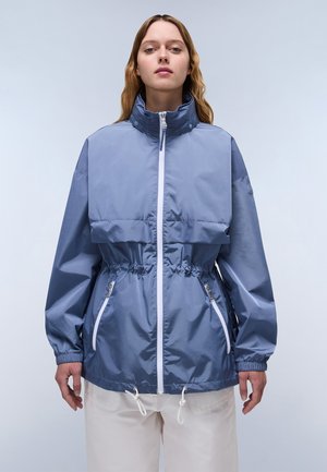 Lichtblauwe nylon windbreaker met een hoge kraag, frontale rits en elastische taille. Voorzien van twee met rits afgesloten zijzakken en een trekkoord onderaan.