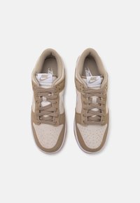 Béžové a krémové tenisky se svrškem z semiše a síťoviny, kulatou špičkou, perforovanými detaily a bílým logem swoosh na boku.