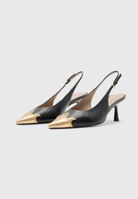 Črne usnjene slingback čevlje s koničastim nosom in metalnimi zlatimi poudarki. Vključujejo klope na nosu in srednje visoko peto.