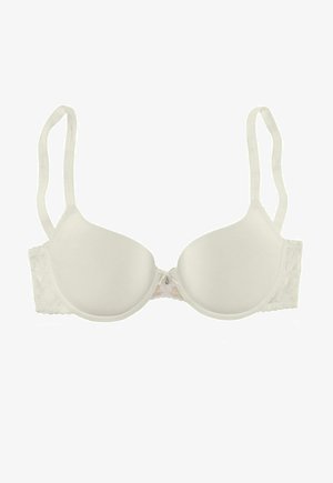 Balts polsterēts krūšturis ar mežģīņu akcentiem sānos, regulējamiem siksniņām un nelielu dekoratīvu striķi vidū. Gluda tekstūra, U veida dizains.