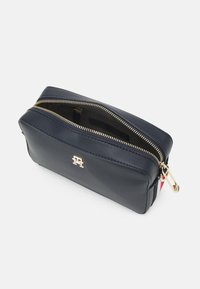Borsa cosmetica in pelle blu navy con cerniera e accessori dorati, caratterizzata da una finitura testurizzata e un logo sul davanti.