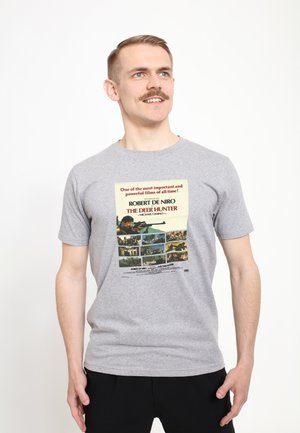 Grå bomulds t-shirt med et grafisk print af filmplakaten til "The Deer Hunter" med tekst og billeder i rød, sort og blå.