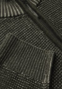 Tmavě zelený pletený svetr s texturovaným vzorem, žebrovanými manžetami, zipovým zapínáním a kontrastní hladkou částí límce.