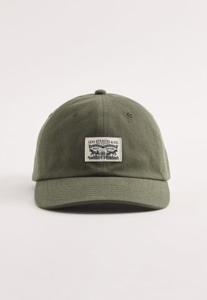 Olivengrøn baseball cap med et rektangulært mærke fra Levi Strauss & Co. med tekst og to heste, der trækker et par jeans.