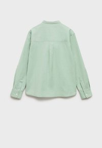 Camicia a maniche lunghe verde chiaro con spallina posteriore, orlo arrotondato, polsini con un solo bottone e tessuto morbido e testurizzato.