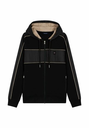 Haut à zip noir avec une capuche beige, présentant des panneaux noirs et des accents beige clair. Comprend deux poches latérales et des cordons de serrage.