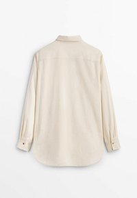 Camicia beige chiara a maniche lunghe con colletto. Taglio dritto, orlo arrotondato e polsini abbottonati. Tessuto liscio e texturizzato.