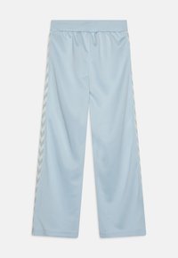 Lyseblå bukser med vide ben, elastisk talje og hvide chevron-striber langs ydersiderne.