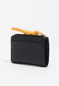 Czarny skórzany portfel z zewnętrzną kieszonką na karty, złotym zamkiem błyskawicznym i żółtym skórzanym uchwytem zamka z dwoma supełkami, na białym tle.