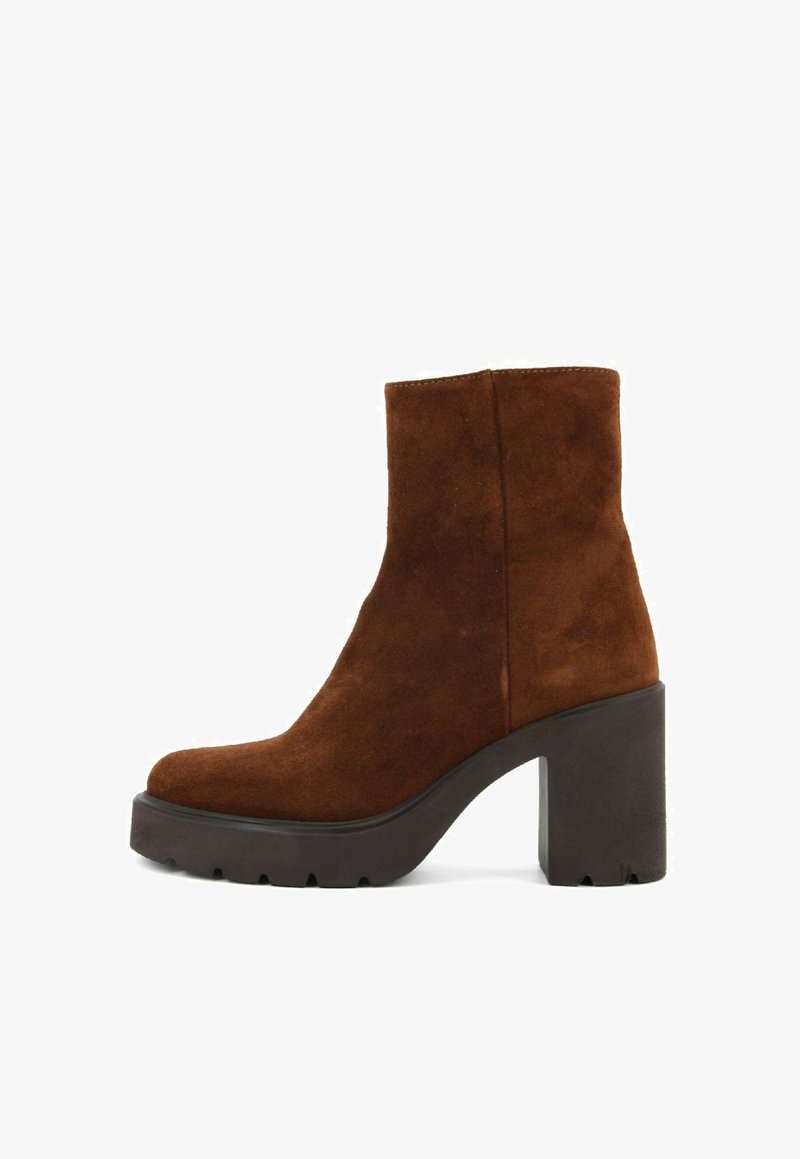 Bottine en daim marron avec une semelle compensée noire épaisse, présentant une finition lisse et un design à bout arrondi.