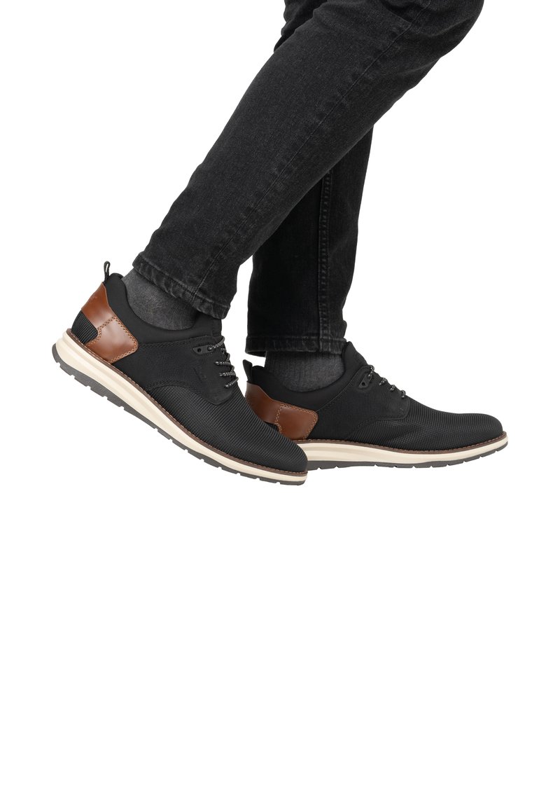 Sneaker in rete nere con dettagli in pelle marrone, dotati di una parte superiore texturizzata, chiusura con lacci e suola in gomma di colore chiaro.