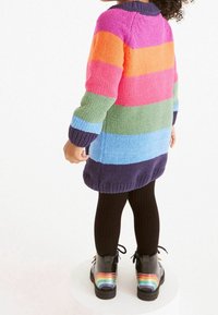 Maglione lavorato a maglia con righe orizzontali in rosa, arancione, verde, blu e blu scuro. Indossato con collant neri e stivali neri con strisce arcobaleno.