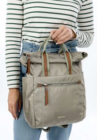 Zaino in nylon grigio con dettagli in pelle, parte superiore arrotolata, doppi manici, tasca con zip anteriore e design elegante. Parte superiore a righe sotto.