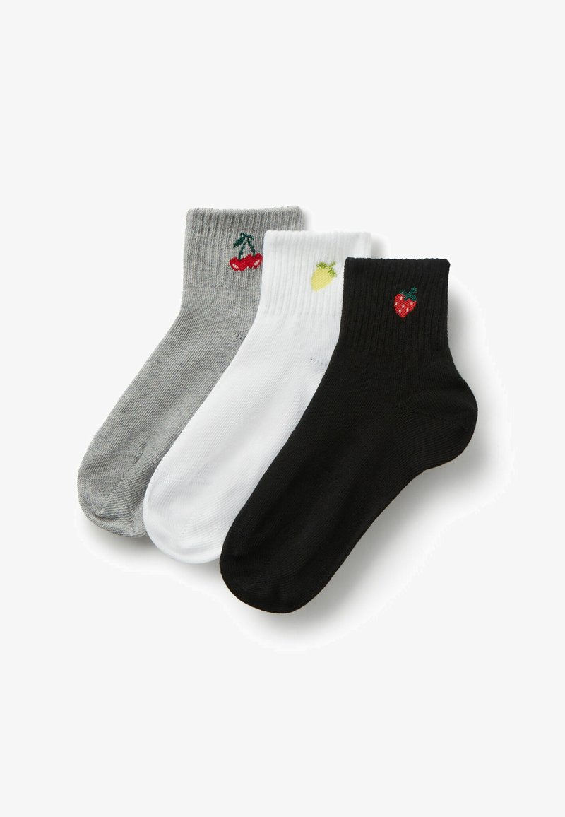 Trois socquettes aux chevilles en gris, blanc et noir, chacune ornée d'un petit fruit brodé : cerises, ananas et fraise.