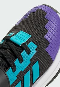 Černá sportovní bota s texturovaným síťovým svrškem. Obsahuje tyrkysové a fialové akcenty, včetně 3D čtvercových vzorů a černých tkaniček.