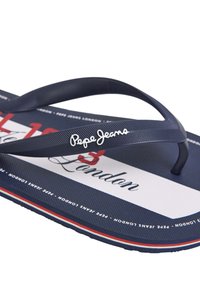 Mornarske japanke z strukturovanimi gumijastimi trakovi. Imajo bel logotip in rdeč accent na modri in beli natisnjeni podlagi. Trajna in sproščena zasnova.